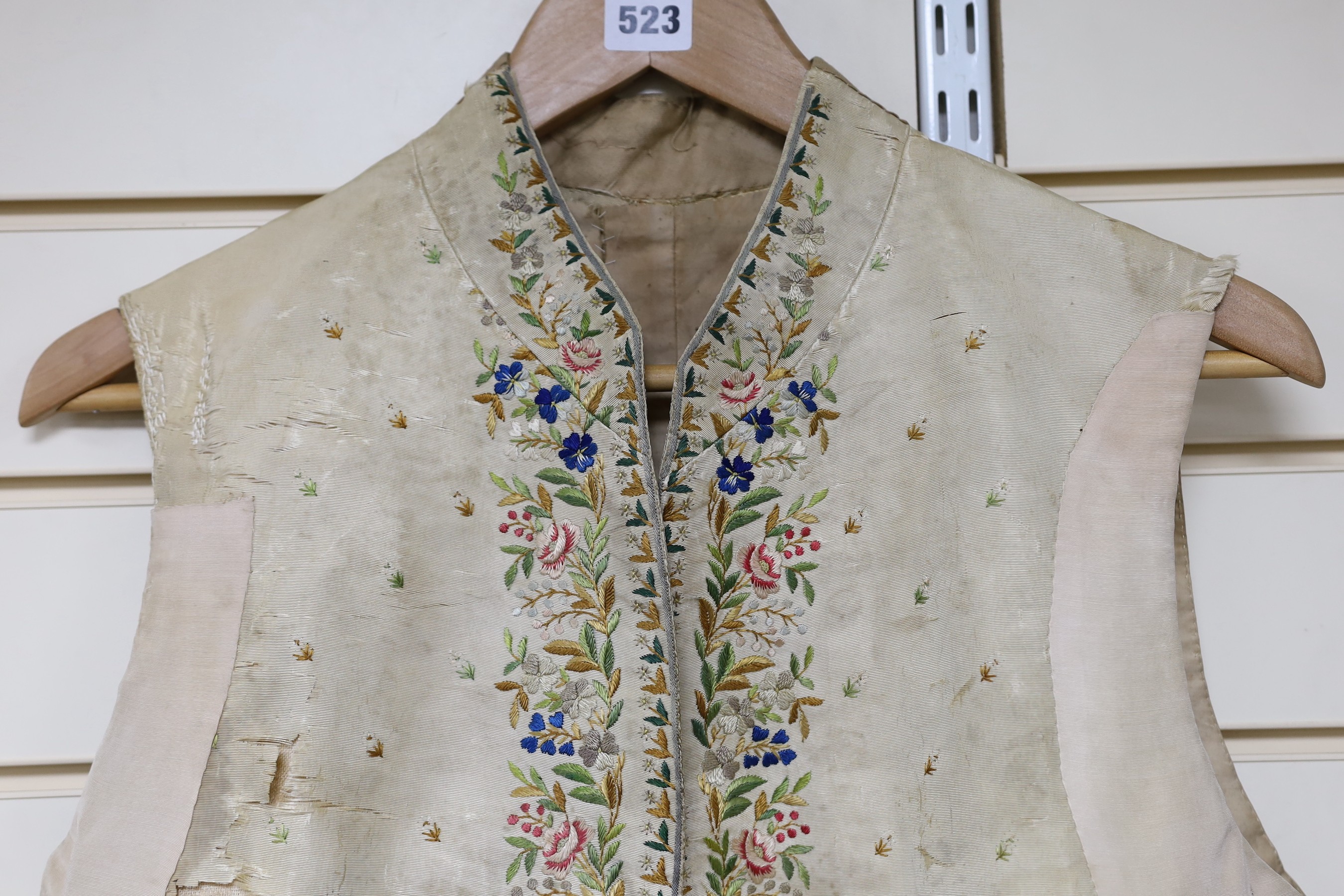 A late 18th early 19th century gentleman’s cream silk waistcoat Embroidered with polychrome silks in a floral design. (The main body of the waistcoat darned and damaged, but the embroidered sections complete).